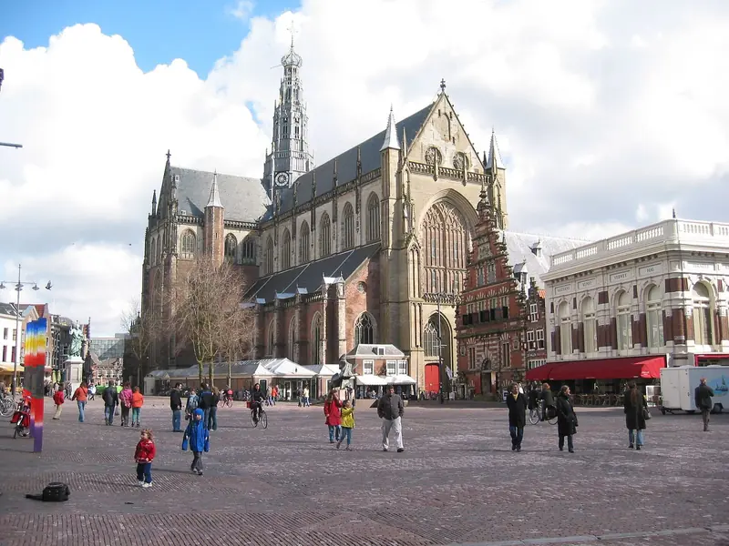 Praça Grote Markt, em Haarlem, com a grande igreja gótica de São Bavão ao fundo e pessoas caminhando no calçamento de tijolos