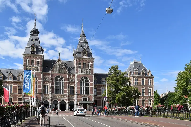 Fachada norte do Rijksmuseum, de tijolo vermelho com duas torres pontudas, num dia de céu azul