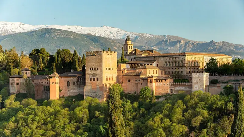 A Alhambra de Granada ao entardecer, vista do Mirador de San Nicolás, com os picos de neve da Sierra Nevada ao fundo