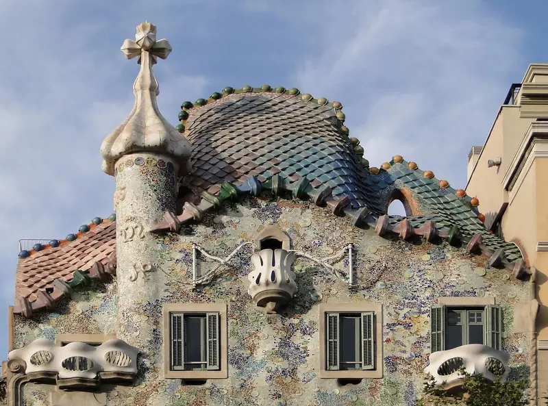 Telhado da Casa Batlló, com telhas que imitam escamas e uma torre com cruz de quatro braços