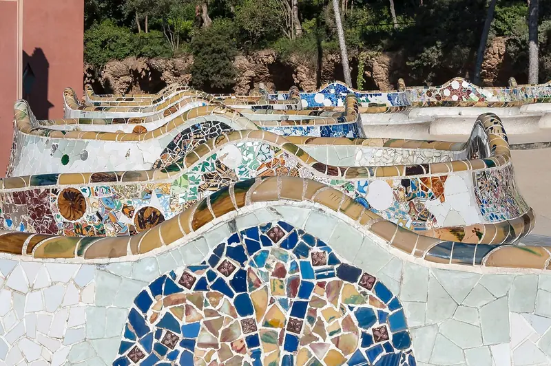 Banco ondulado coberto de mosaico de cerâmica colorida na praça principal do Park Güell