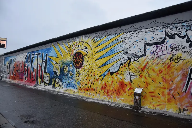Mural colorido com a frase Save our Earth pintado num longo trecho do Muro na East Side Gallery, num dia nublado