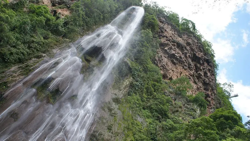 Cachoeira Boca da Onça vista de baixo, descendo por um paredão coberto de vegetação