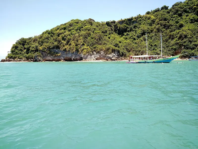 Escuna de dois mastros ancorada em água verde-turquesa ao lado da Ilha Feia