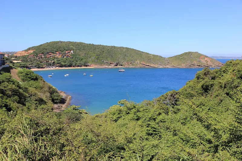 Enseada de João Fernandes vista do alto do morro, com barcos ancorados e casas na encosta