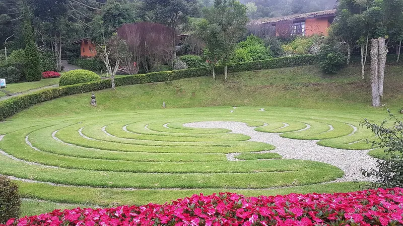 Labirinto circular de grama cercado de flores cor-de-rosa no Parque Amantikir