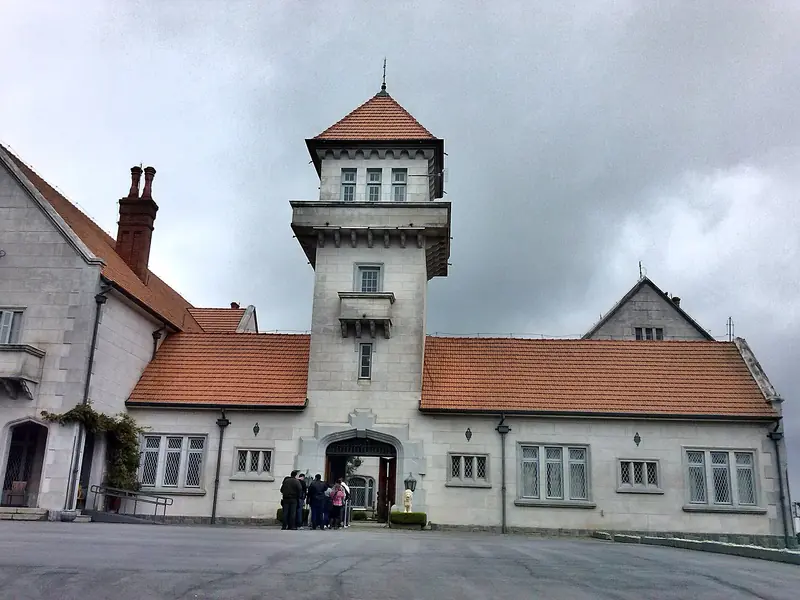 Fachada de pedra clara com torre central e telhado de telhas vermelhas do Palácio Boa Vista, sob céu nublado