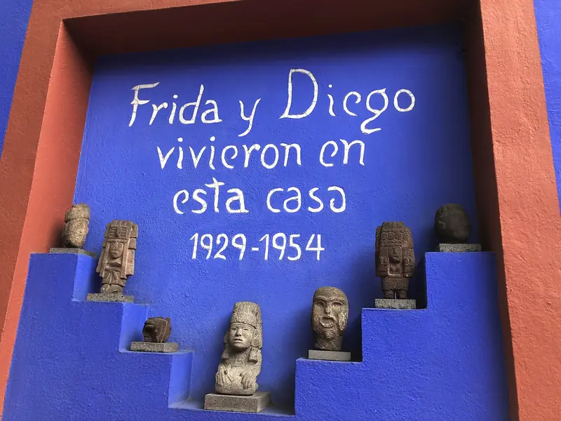 Nicho azul-cobalto no pátio da Casa Azul com a inscrição Frida y Diego vivieron en esta casa 1929-1954 e pequenas esculturas pré-hispânicas em degraus