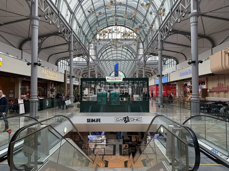 Galeria do shopping de Val d'Europe com teto de vidro em arco, lojas dos dois lados e escadas rolantes
