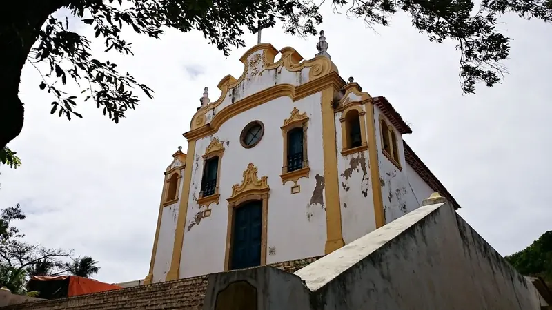 Fachada branca e amarela da igreja de Nossa Senhora dos Remédios, vista de baixo