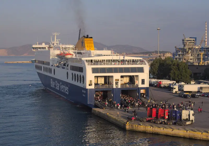 Ferry da Blue Star atracado no porto do Pireu, com passageiros e caminhões desembarcando pela rampa
