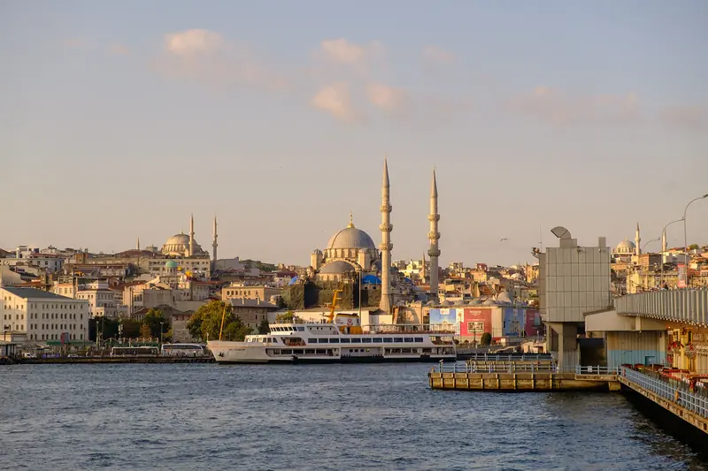 A orla de Eminönü vista da ponte de Gálata, com um ferry atracado, a Mesquita Nova no centro e a Süleymaniye no alto à esquerda, no fim da tarde
