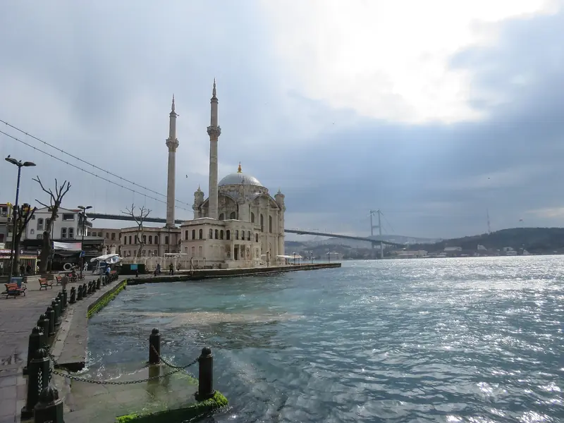 Mesquita de Ortaköy à beira do Bósforo, com a ponte suspensa ao fundo e o céu carregado