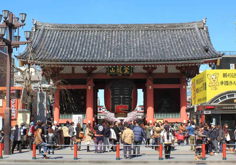 Portão Kaminarimon do templo Sensoji, com a grande lanterna vermelha no centro e visitantes na frente