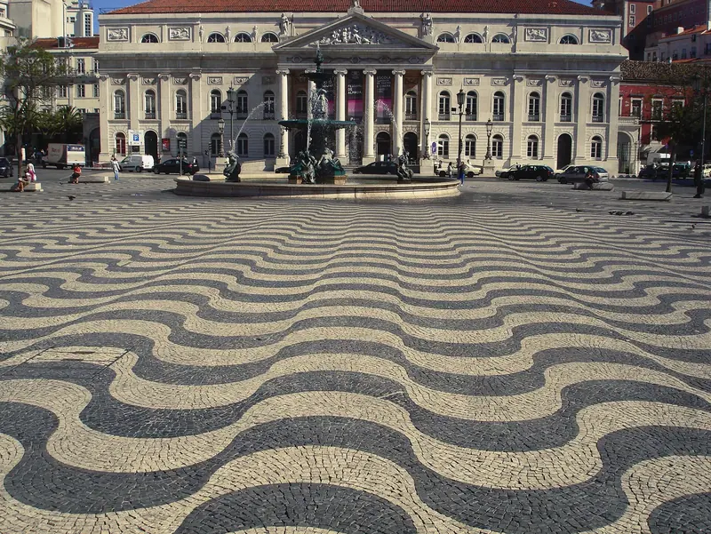 Calçada em ondas pretas e brancas na Praça do Rossio, com o Teatro Nacional ao fundo