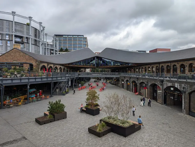Pátio do Coal Drops Yard, em King's Cross, com os antigos armazéns de tijolo e os telhados curvos que se encontram no centro