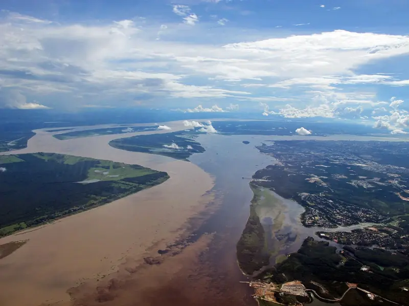 Vista aérea do Encontro das Águas, com o Rio Negro escuro e o Solimões barrento correndo lado a lado perto de Manaus