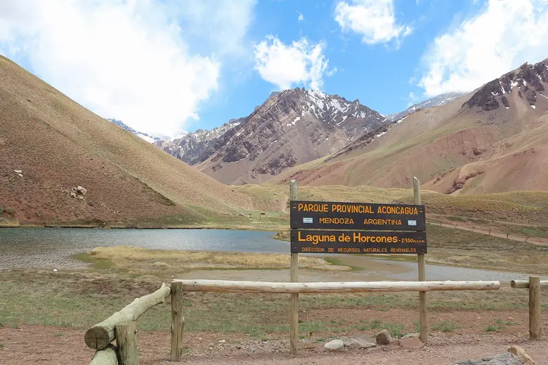 Placa da Laguna de Horcones, a 2.950 metros, diante da lagoa e de montanhas com neve