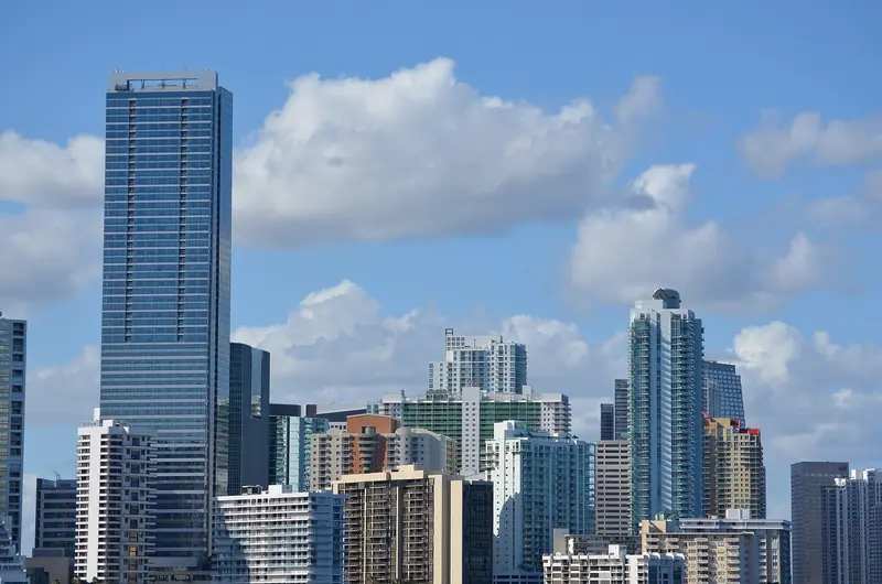 Torres de vidro e prédios residenciais de Brickell sob céu azul com nuvens, vistos de longe