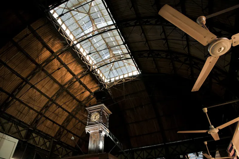 Teto de madeira e ferro do Mercado del Puerto, com claraboia de vidro e o relógio de ferro no centro