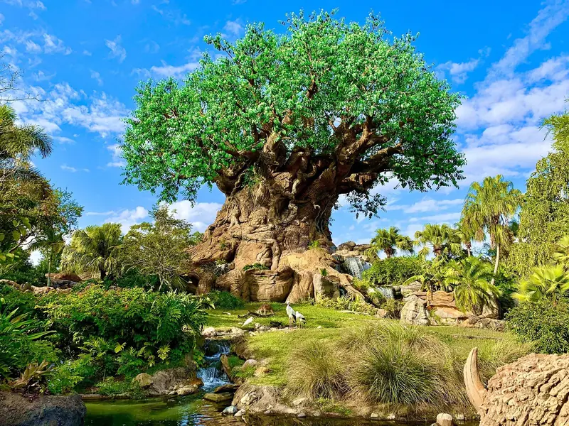 Árvore da Vida do Animal Kingdom, com tronco esculpido em formas de animais, cercada de vegetação e um riacho