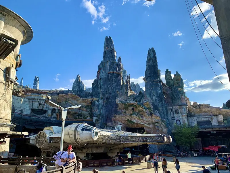 Millennium Falcon em tamanho real diante das torres de pedra da área de Galaxy's Edge, sob céu azul