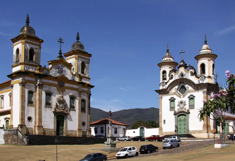 Praça Minas Gerais em Mariana com as igrejas de São Francisco de Assis e do Carmo sob céu azul