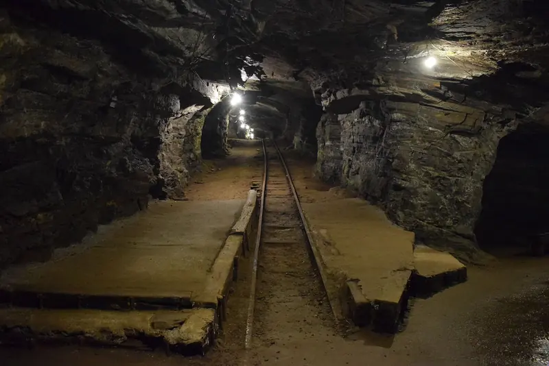 Galeria subterrânea iluminada da Mina da Passagem com trilhos no chão