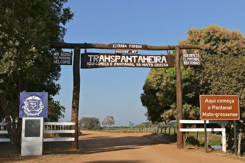 Portal de madeira da Estrada Parque Transpantaneira, com a estrada de terra seguindo ao fundo