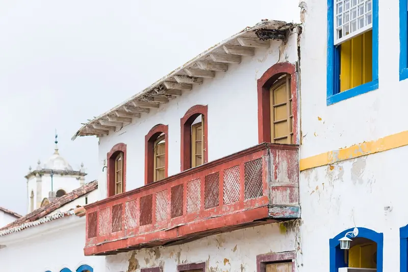 Sobrado com balcão de treliça vermelho e janelas coloridas no centro histórico