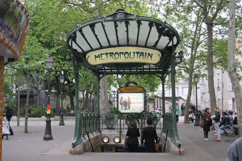 Entrada art nouveau da estação de metrô Abbesses, com a placa Metropolitain em cobertura de vidro e ferro verde