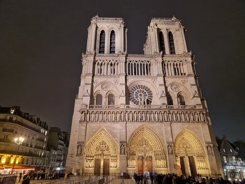 Fachada de Notre-Dame iluminada à noite, com as duas torres e a rosácea central