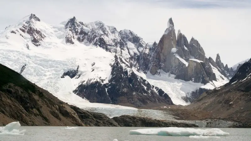 Laguna Torre com pequenos icebergs na água, o glaciar descendo até a margem e o Cerro Torre ao fundo