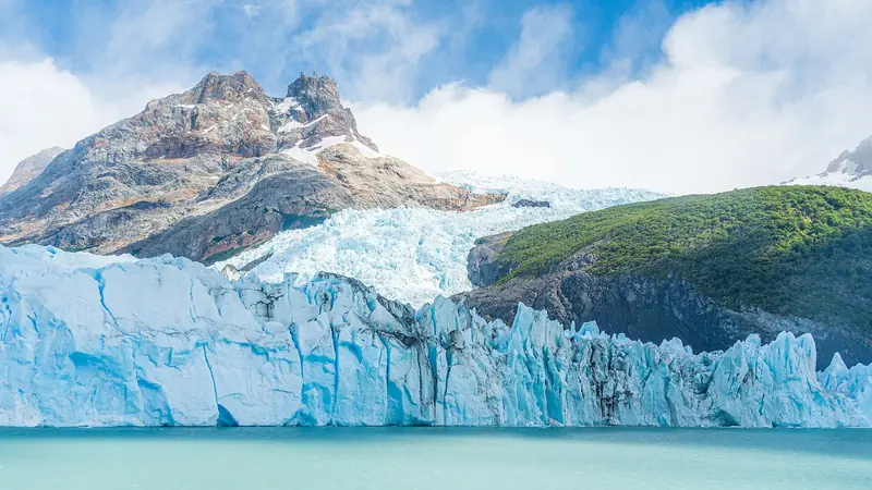 Parede de gelo azul do Glaciar Spegazzini, com montanha de rocha avermelhada ao fundo