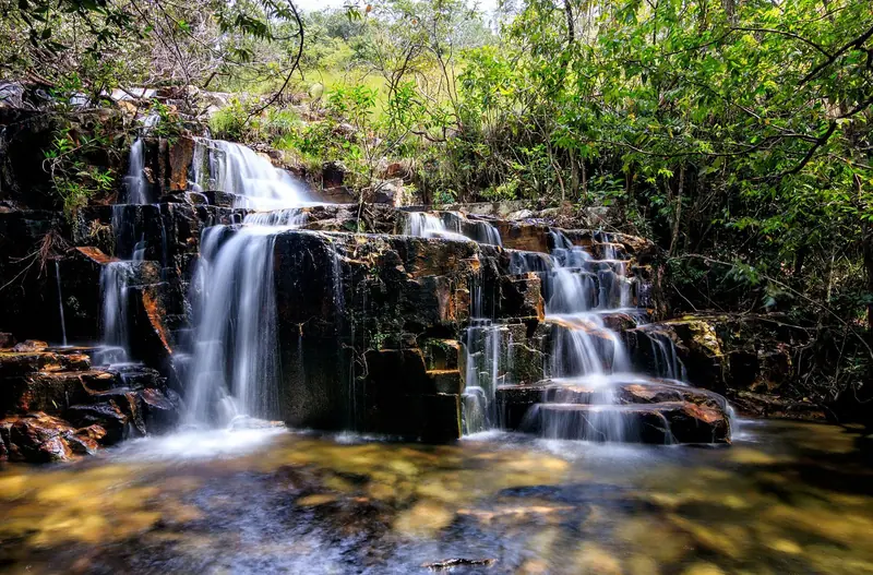 Cachoeira Nuvens do Dragão descendo em degraus de pedra no meio da mata