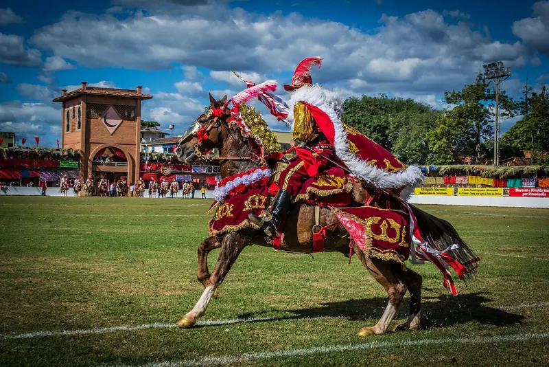 Cavaleiro de vermelho, do lado mouro, a galope com o cavalo enfeitado