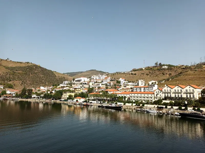 Vila do Pinhão na margem do rio Douro, com encostas de vinhedos em socalcos ao fundo
