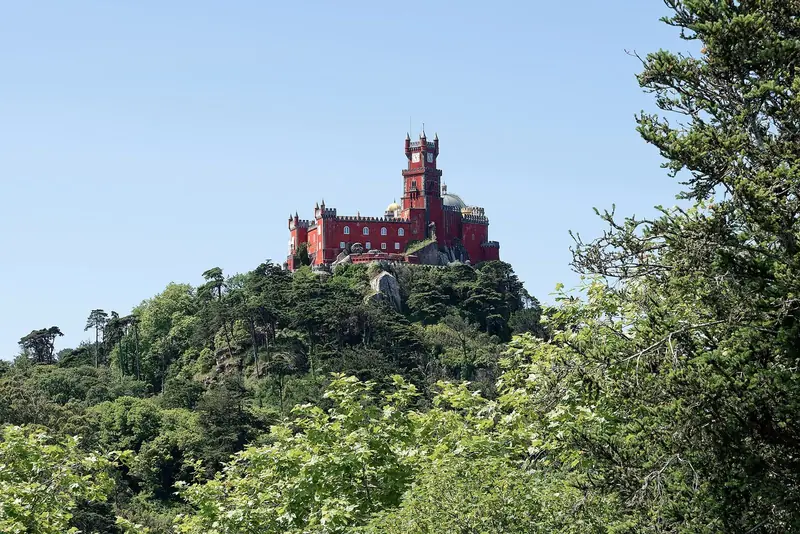 Palácio da Pena, vermelho, no alto da serra de Sintra, cercado de mata