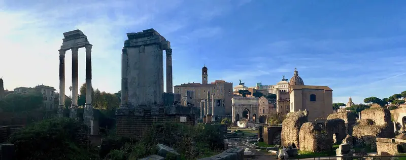 Ruínas do Fórum Romano com as três colunas do Templo de Castor e Pólux à esquerda e o Arco de Sétimo Severo ao fundo