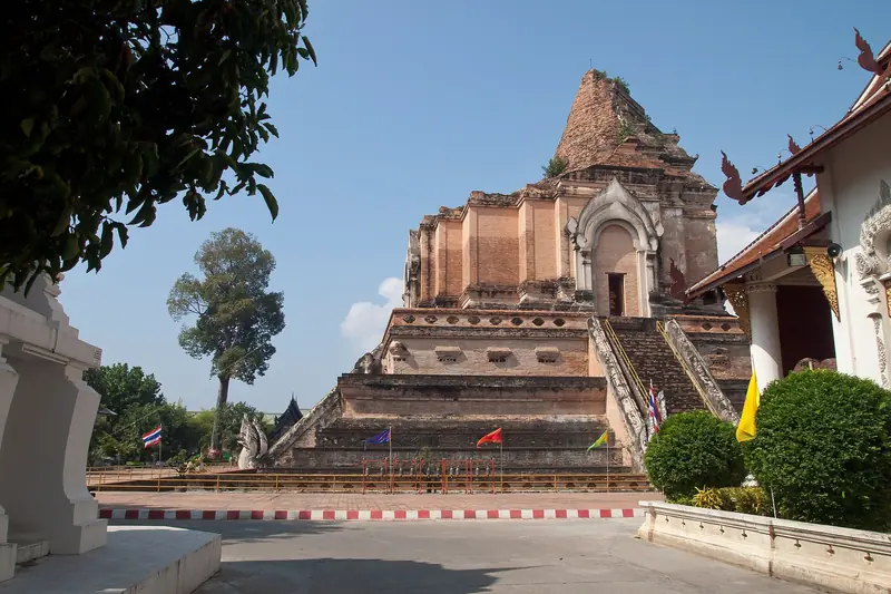 Torre de tijolos do Wat Chedi Luang com escadaria guardada por serpentes de pedra, sob céu azul