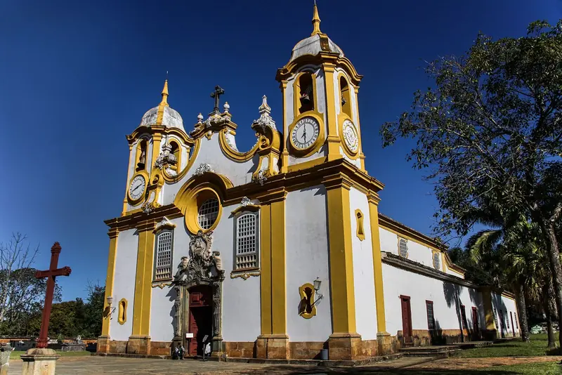Fachada branca e amarela da Igreja Matriz de Santo Antônio, em Tiradentes, sob céu azul