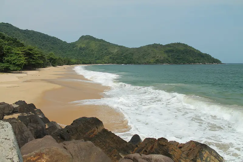 Praia Grande do Bonete vista das pedras do canto, com areia dourada, ondas na beira e morros de mata atlântica